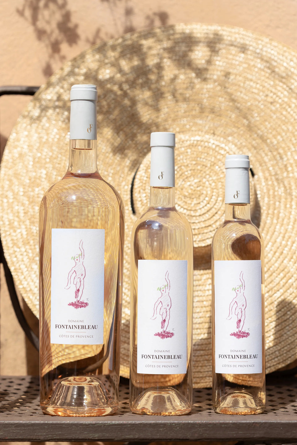 Trois bouteilles de rosé de la collection Provence et un chapeau de paille — Domaine Fontainebleau en Provence