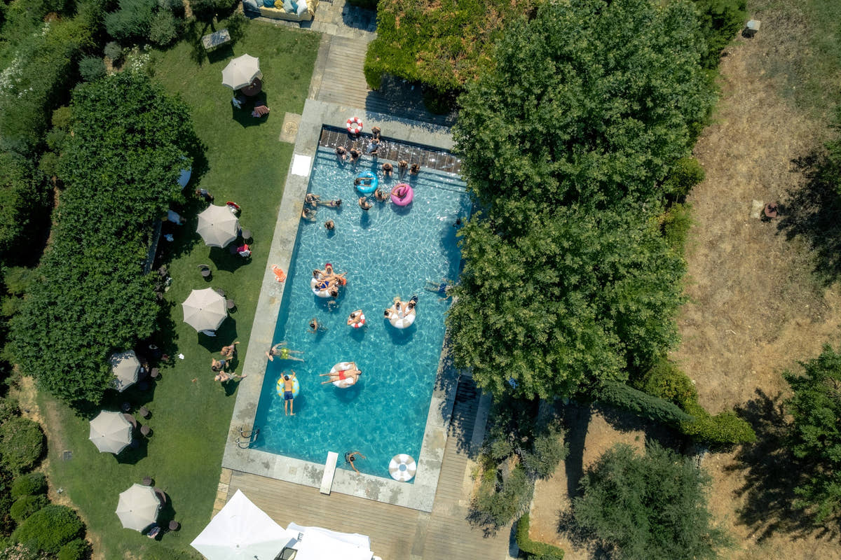 La piscine du domaine vue du ciel, entre parasols et grands arbres — Domaine Fontainebleau en Provence